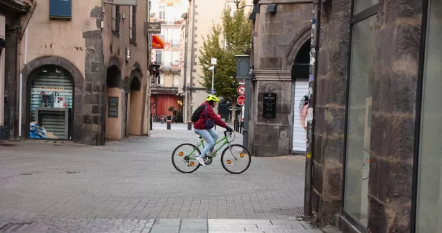 Cycliste traversant une zone piétonne à Clermont-Ferrand, en lien avec l'arrêté "Pied à terre" pour la sécurité.