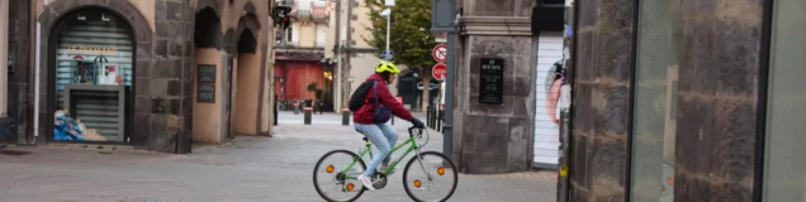 Cycliste traversant une zone piétonne à Clermont-Ferrand, en lien avec l'arrêté "Pied à terre" pour la sécurité.